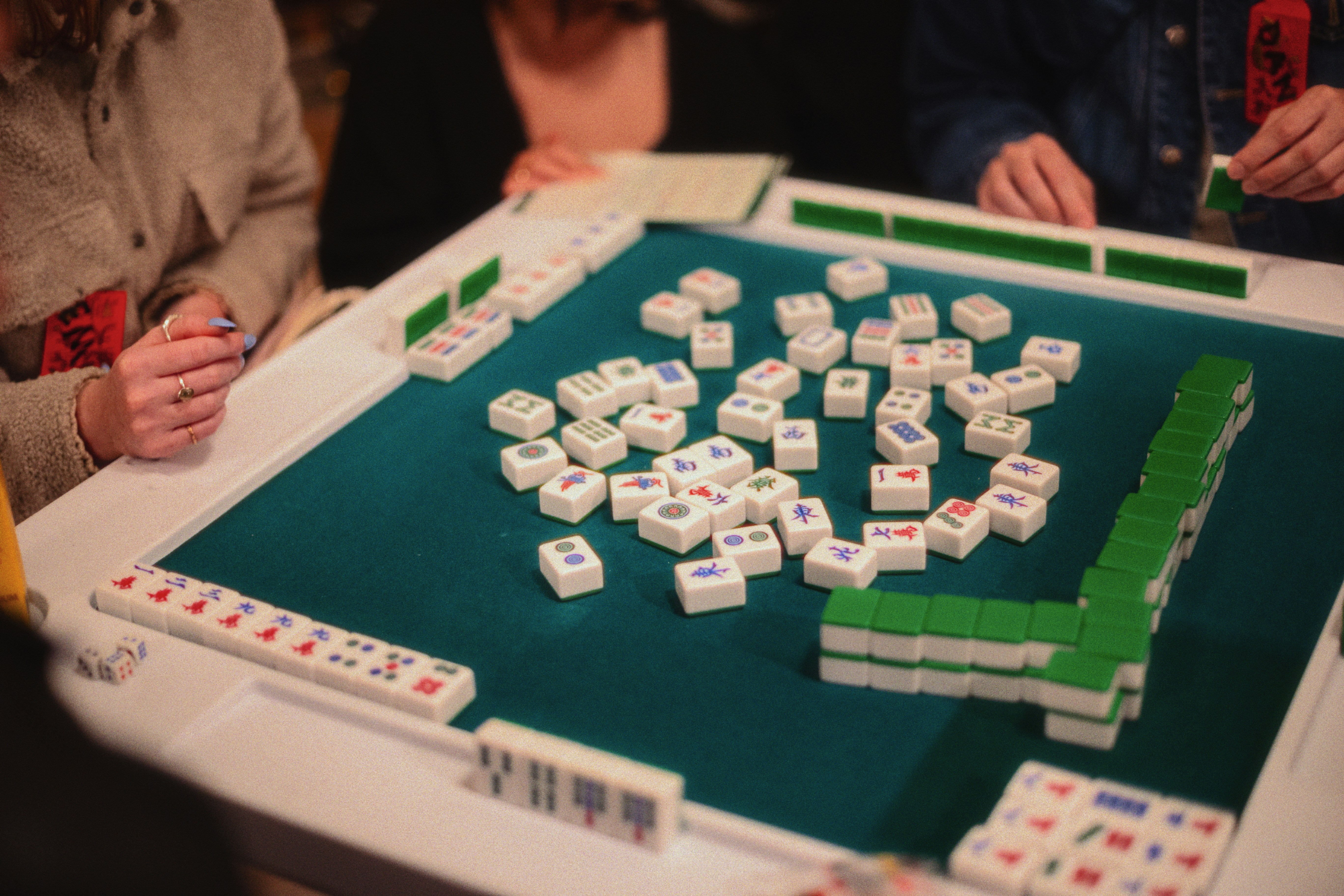 Mahjong tiles on table with person in background. Photo by Jason Leung on Unsplash