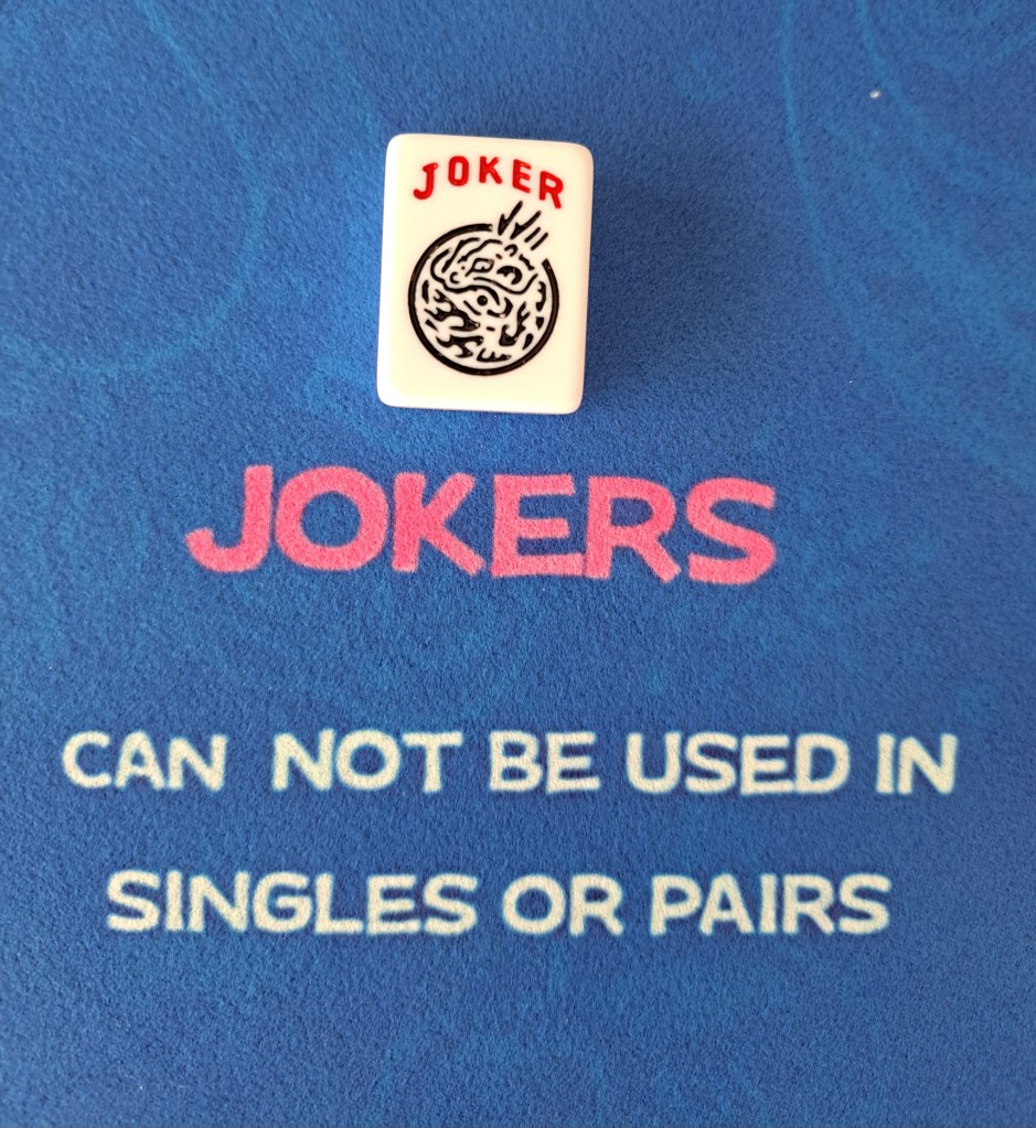Joker tile with writing that jokers can not be used in singles or pairs.