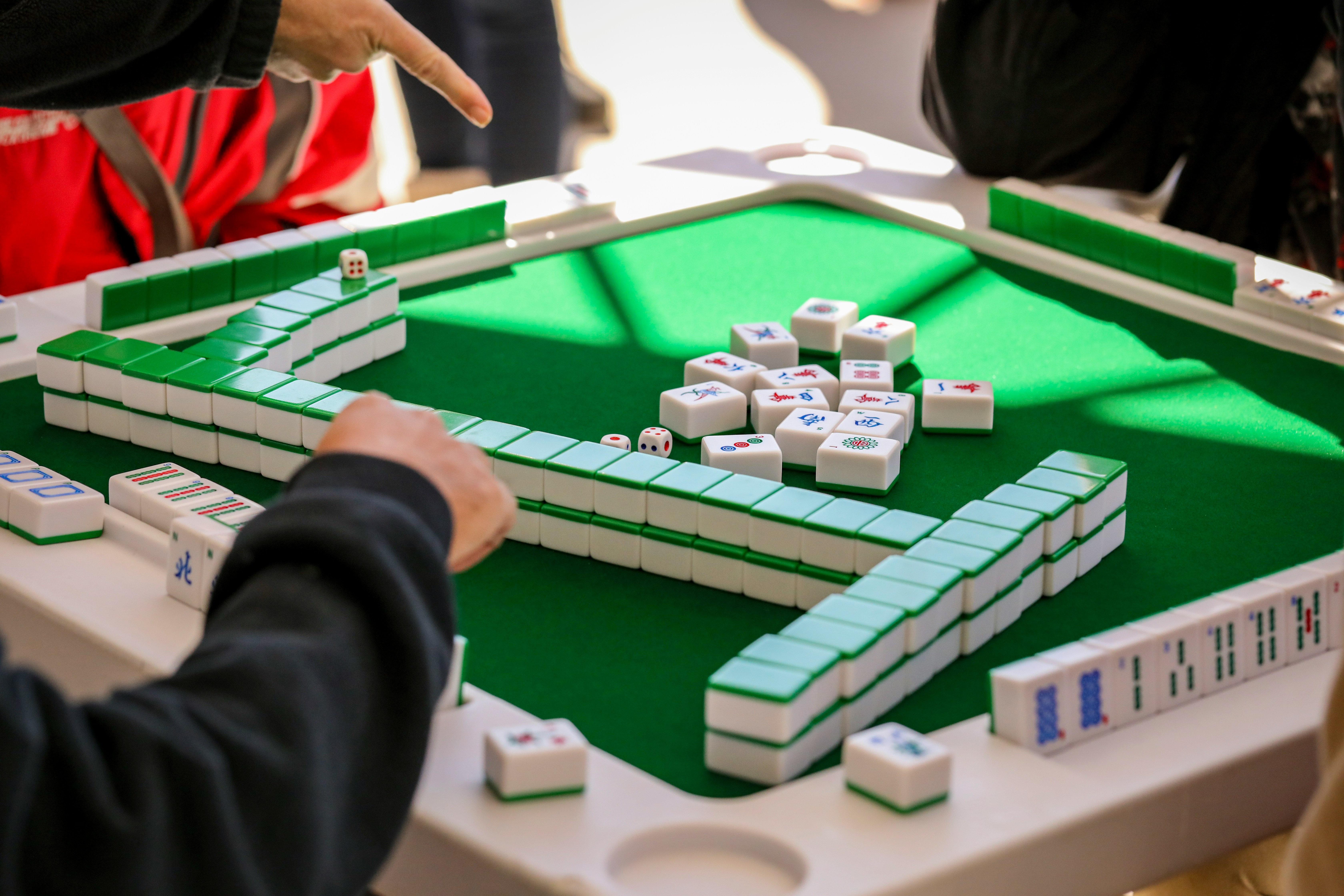 Hand above mahjong tiles. 
Photo by Mick Haupt on Unsplash
