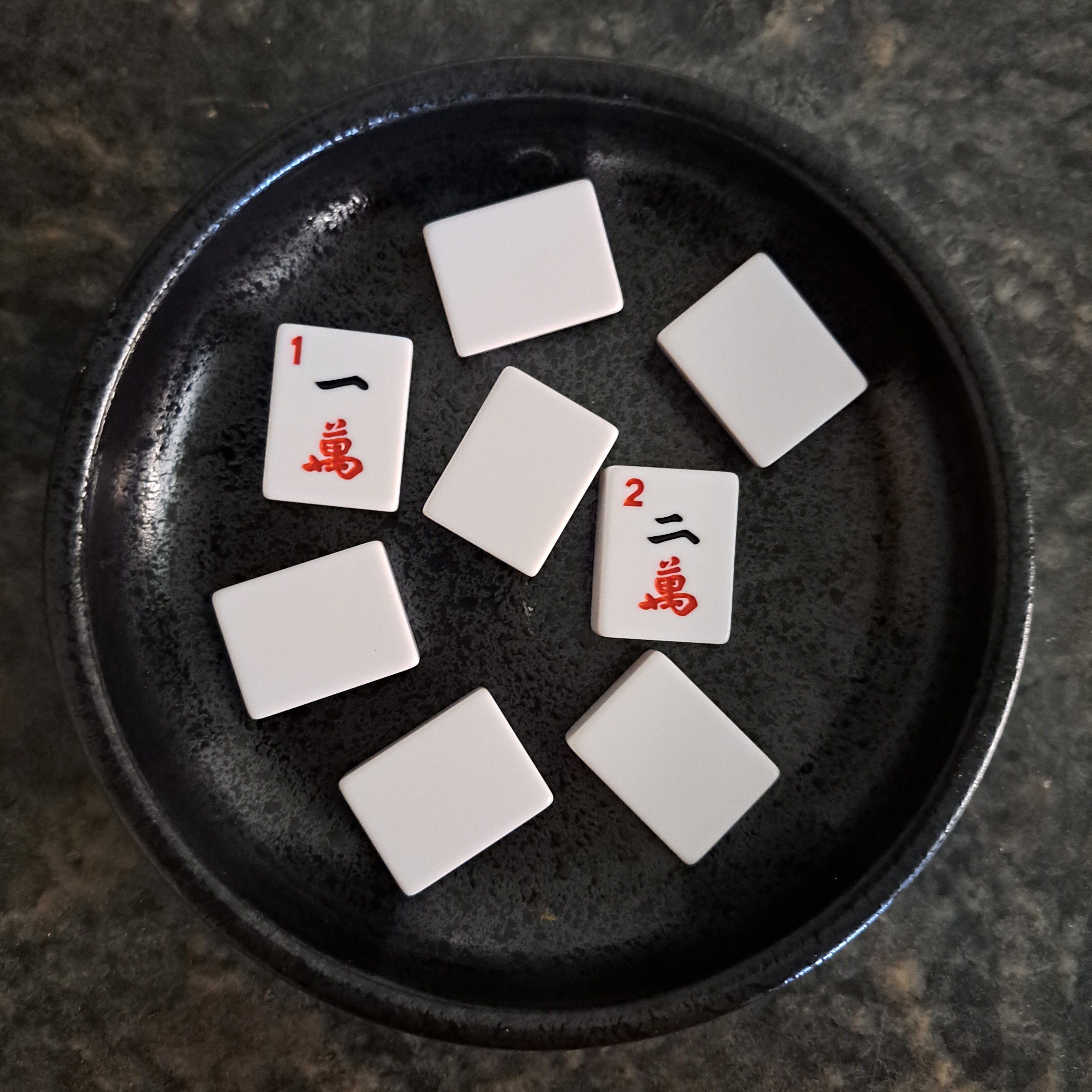 Players draw numbered Mahjong tiles from a bowl to randomly assign themselves to tables—1s go to Table 1, 2s to Table 2, and so on.