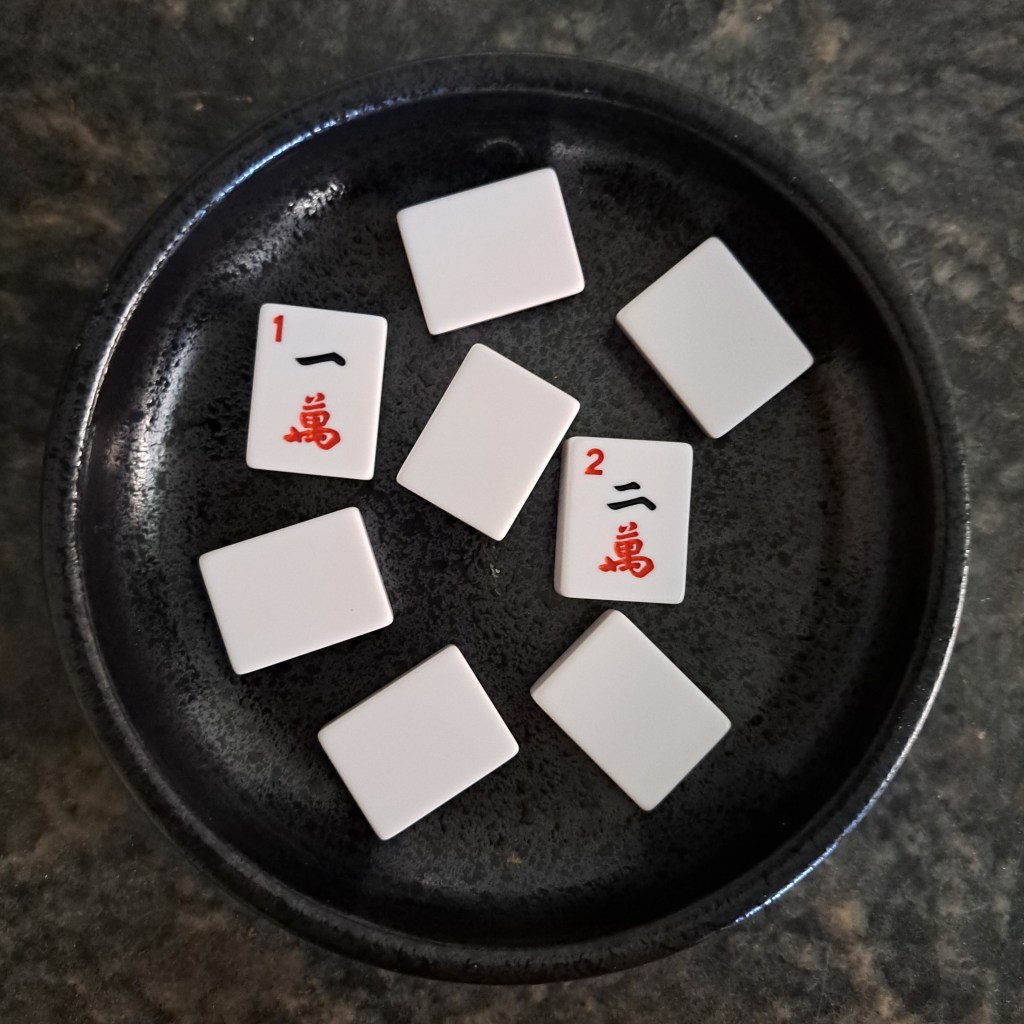 Players draw numbered Mahjong tiles from a bowl to randomly assign themselves to tables—1s go to Table 1, 2s to Table 2, and so on.