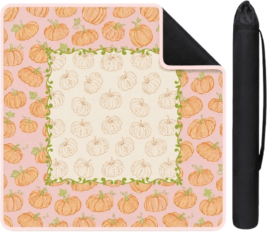A picnic blanket with a decorative pumpkin pattern, featuring orange and cream-colored pumpkins on a pink background, bordered by green vines.